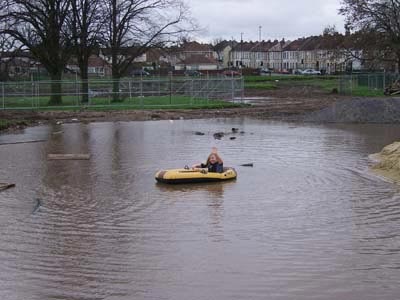 Someone sits in an inflatable boat in a large puddle